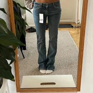 Blå lågmidjade jeans från Zara - Snygga blå bootcut jeans från Zara med klassisk femficksdesign. De har en bekväm passform och är perfekta för en avslappnad stil. Använda några få gånger, i jättebra skick