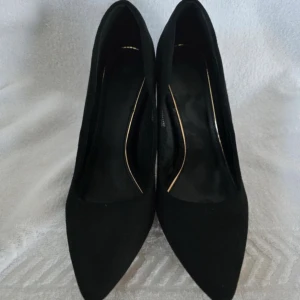 Svarta pumps med spetsig tå - Eleganta svarta pumps med spetsig tå och klack. Perfekta för en stilren look. Skorna har en klassisk design som passar till många olika tillfällen. Har inga defekter, bara sulan under skon som är lite smutsig. Storlek 40 men kan passa 39.