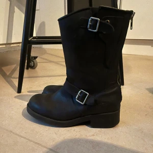 Svarta boots med spännen och dragkedja - Johnny Bulls                                                 Snygga svarta boots i skinn med robusta spännen och dragkedja baktill. 