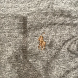 Grå halfzip från Polo Ralph Lauren - Säljer en stilren grå tröja från Polo Ralph Lauren med dragkedja och broderad logotyp på bröstet. Tröjan har storlek S och är i väldigt fint skick. Hör av dig vid minsta fundering!