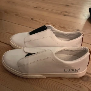 Vita sneakers från Lauren Ralph Lauren - Snygga vita sneakers från Lauren Ralph Lauren med elastisk detalj för enkel på- och avtagning. köpta på vinted så vet ej om de är äkta men är ganska säker på att de är de, men därav de billiga priset 