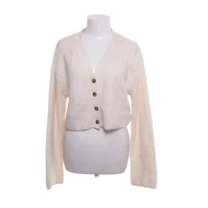 Beige kofta med knappar - Säljer en mysig beige kofta med knappar framtill. Koftan har en v-ringad design och långa ärmar.