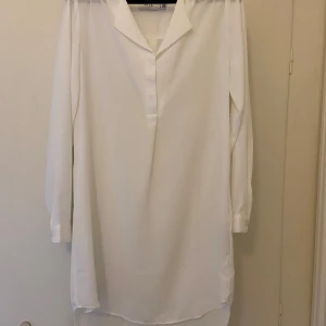 Vit långärmad tunika från Vila - Snygg vit tunika från Vila med långa ärmar och en stilren design.  Endast använd 1 gång 