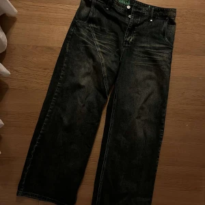 Jeansbyxor Protémoa - Säljer ett par svarta jeansbyxor från Protémoa i storlek L. Byxorna har en loose passform med en klassisk femficksdesign och subtila slitningar för en cool look. Perfekta för en avslappnad stil. Bra condition, bara använda ett fåtal gånger. Har lite heeldrag men märks knappt. Originalpris 1000kr