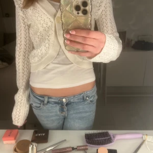 Vit stickad kofta - Säljer en vit stickad kofta med ett fint hålmönster. Koftan har långa ärmar som är lite smått utsvängda (se bild). 