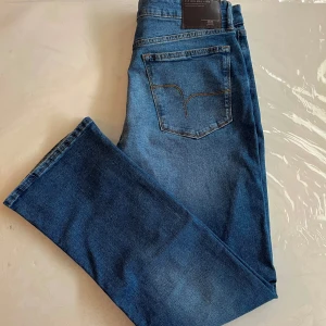 Blå jeans baggy - Helt nya. Snygga blå jeans från Flying Machine med klassisk femficksdesign och dragkedja. Perfekta för en avslappnad stil. De har en normal passform och är tillverkade i slitstarkt denim.