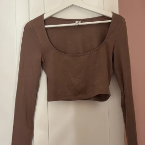 Brun croppad topp från NLY Trend - Säljer en brun croppad topp från NLY Trend. Toppen har långa ärmar och en rundad halsringning. Perfekt för en stilren look.