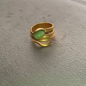 Handgjord guldpläterad ring med opalsten - Handgjord guldpläterad ring  med en vacker grön opal sten i mitten. Ringen har en unik design med flera lager som ger ett modernt och stilrent utseende. Perfekt för att ge en touch av färg och elegans till din outfit.