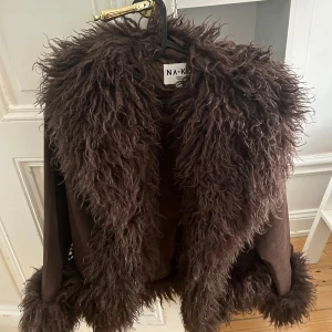 Brun pälsjacka NA-KD moa mattsson  -  brun jacka från NA-KD med fluffiga pälsdetaljer runt krage och ärmslut.  36, använd fåtal ggr 