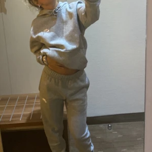 Grå hoodie och mjukis från Nike - Säljer en grå hoodie och gråa mjukis från Nike med en klassisk passform. Tröjan har en justerbar huva med dragsko och en liten Nike-logga på bröstet. Perfekt för en avslappnad stil.