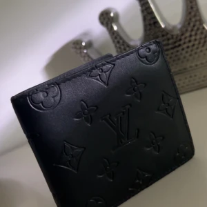 Svart plånbok från LW - Säljer en stilren svart plånbok från LW med det klassiska monogrammönstret. Plånboken har flera fack för kort och en sektion för sedlar. Perfekt för den som vill ha en lyxig och praktisk accessoar. 🖤