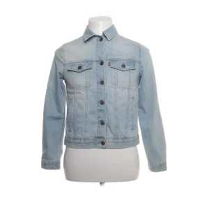 Ljusblå jeansjacka från Lexington - Säljer en snygg ljusblå jeansjacka från Lexington. Jackan har en klassisk design med knappar framtill och två bröstfickor med lock. Tillverkad i 100% bomull för en bekväm passform. Perfekt för en avslappnad stil.