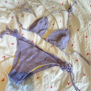 Lila stickad bikini - Snygg lila stickad bikini med trekantsöverdel och knytband. Perfekt för sommarens stranddagar. Underdelen har knytning på sidorna för justerbar passform. Handmade