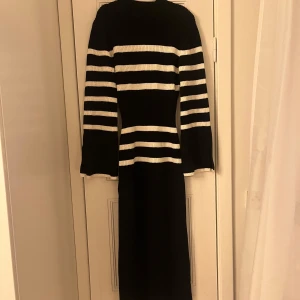 Svart och vit randig klänning adoore - Snygg svart och vit randig klänning med lång ärm och ribbad design från adoore. (Lånat bilden med klänningen på, min har ingen slits och vidare armar. Men sitter liknande därav la jag in den som referens) 