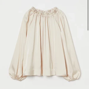 Beige blus med knytband - Säljer en superfin beige blus med långa ärmar och ett snyggt knytband vid halsen. Blusen har en lös passform och är perfekt för både vardag och fest. Materialet känns lyxigt och faller fint. Köpt för 299kr säljer för endast 120kr.