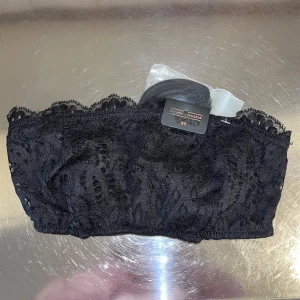 Svart spets topp från BIK BOK Lingerie - Säljer en elegant svart spets topp från BIK BOK Lingerie. Toppen har ett vackert spetsmönster och en bekväm passform. Perfekt för att lägga till en touch av stil till din outfit.