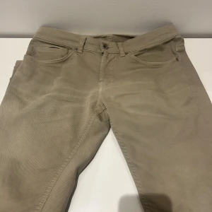 Beige byxor från Dondup - Snygga beige byxor från Dondup, tillverkade i Italien. De har en klassisk femficksdesign med knapp och dragkedja framtill. Perfekta för en stilren look.