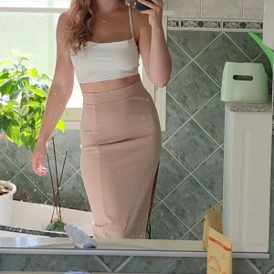 Beige långkjol med slits - Snygg beige långkjol med en stilren slits på sidan. Perfekt för en chic look. Kjolen har en tight passform som framhäver figuren. Kjolen är i storlek XS/S