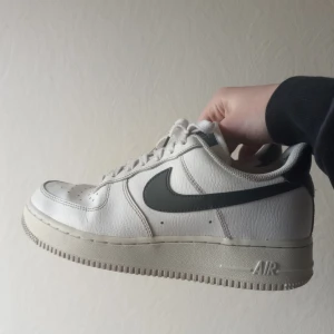 Vita Nike Air Force sneakers - Säljer ett par klassiska vita Nike Air Force sneakers med en svart Nike logga. Skorna är slitna på båda bakkapporna (se bild 2). Annars är de i jättebra skick. Säljer pågrund av för små. Använda ungefär ett halvår. Fler bilder kan skickas privat. 