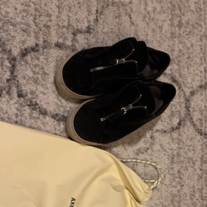 Svarta sneakers från Axel Arigato - Säljer mina arigatos som inte säljs längre, storlek 40, ganska använda och kommer med bara dustbag. Ingen originalsula och har en defekt vid dragkedjan inget synligt.