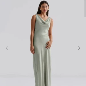 Balklänning  - Elegant ljusgrön långklänning med draperad halsringning. Klänningen är ärmlös och har en mjuk, flytande passform som ger en sofistikerad look. Perfekt för speciella tillfällen. Aldrig använd, helt ny med prislappar samt förpackning kvar🥰