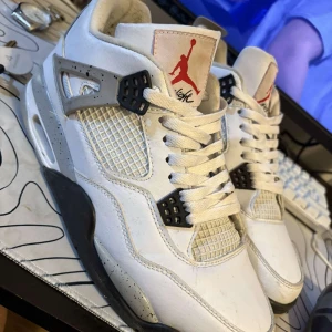 Nike Air Jordans i vitt och svart - Snygga Nike Air Jordans i vitt med svarta och röda detaljer. Skorna har en klassisk design med snörning och det ikoniska Jumpman-logotypen på plösen. Perfekta för dig som vill ha en stilren och sportig look.