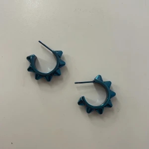 Blå örhängen med nitar från Edblad - Snygga blå örhängen med nitar i en cool design. Perfekta för att ge en edgy touch till din stil. De har en rund form och är lätta att bära.