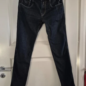 Mörkblå jeans från Replay 30/32 - Mörkblå jeans från Replay, modell Anbass. Strl 30/32. Femficksdesign och bekväm passform. Fint skick. Välkommen att höra av er med eventuella frågor eller funderingar.