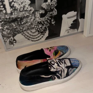 slip-ons från Limitato - Jättecoola och Unika slip-ons från Limitato. Skorna har en mix av leopardmönster och graffiti i nyanser av rosa, blått och svart. De har en svart sula och är tillverkade i Italien. Säljer pga för stora
