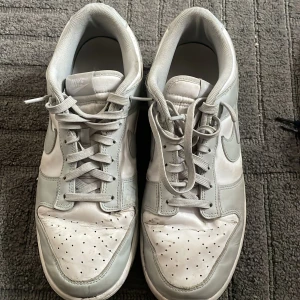  Nike Dunk skor - Säljer ett par Grå vita Nike Dunks, Nypris 1500. Skorna är använda men är i hyfsat skick. Storlek 45, UK 10. Lägre pris kan diskuteras.