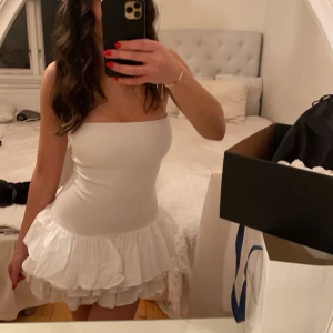 Vit klänning från Zara - Säljer en söt vit klänning från Zara med volangdetaljer. Klänningen är axelbandslös och har en kort längd som ger en lekfull look. Perfekt för sommarens alla tillfällen!