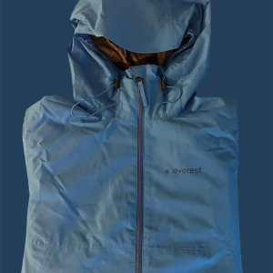Blå vindjacka från Everest - Säljer en blå vindjacka från Everest med huva och dragkedja framtill. Jackan har en stilren design och är perfekt för blåsiga dagar. Den är lätt och smidig att bära med sig.