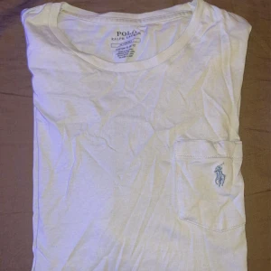 Ljus blå t-shirt från Polo Ralph Lauren - Säljer en ljus blå t-shirt från Polo Ralph Lauren med en broderad logga på bröstfickan. T-shirten har en slim passform och är tillverkad i mjuk bomull. Perfekt för en stilren och avslappnad look.