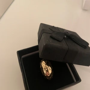Guldfärgad ring - Elegant guldfärgad ring med en unik, ojämn yta som ger ett modernt och stilrent intryck. Perfekt för att ge en touch av lyx till din outfit. Kommer i en snygg svart presentask. (Inte äkta guld)