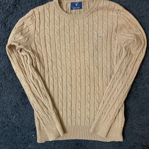 Beige kabelstickad tröja från GANT - Säljer en stilren beige kabelstickad tröja från GANT i stretchig bomull. Den passar Str XS/S
