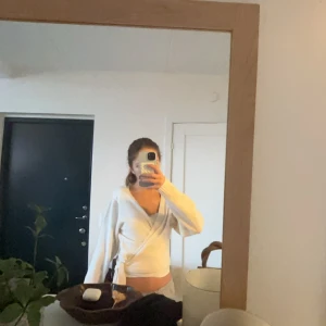 Populär vit knytkofta  - Säljer en mysig vit omlottkofta med knytning i sidan. Koftan har långa ärmar och är perfekt för en stilren eller mysig look. Den är gjord i ett mjukt material som känns skönt mot huden. Säljer den för att håller på att försöka spara pengar men och har endast andvänt den cirka 3 gånger. Den e från Zalando men märket heter even&odd🤍🤍🤍