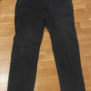 Marinblå chinos - Snygga marinblå chinos med normal passform och raka ben. De har praktiska fickor fram och bak, samt knappar vid bakfickorna. Perfekta för en stilren look.
