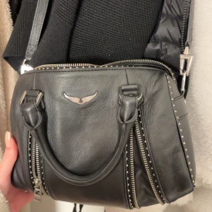 Zadig väska - Intressekol! Snygg svart skinnväskai medelstorleken med coola dragkedjedetaljer och ett stilrent emblem framtill. Väskan har både handtag och en justerbar axelrem med nitar, skriv om mer bilder elelr frågor! Äktehetsbevis finns❤️