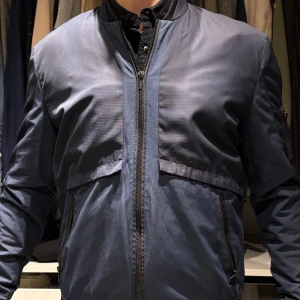 Zara Blå vår/sommarjacka. M - Snygg blå jacka med dragkedja framtill och ribbad krage. Jackan har en stilren design med långa ärmar och praktiska fickor med dragkedja. Perfekt för en cool och avslappnad stil.