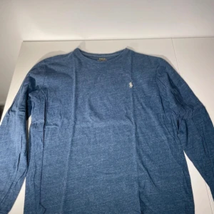 Ralph Lauren - Storlek M, Säljer en blå tröja från Polo Ralph Lauren. Tröjan har en liten broderad logotyp på bröstet och är tillverkad i ett mjukt material för extra komfort. Perfekt för en avslappnad och snygg look.