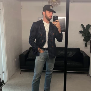 Randig kavaj i blått - Snygg blå randig kavaj med dubbelknäppning. Perfekt för en stilren look. Passar bra med jeans eller chinos för en avslappnad men ändå uppklädd stil. Finns en nederdel till som jag inte får på mig. Samt en väst. Allt i ull. Difficult b p är märket.