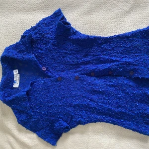 Blå spetstopp från Myrine - Snygg blå spetstopp från Myrine med korta ärmar och knappar framtill. 