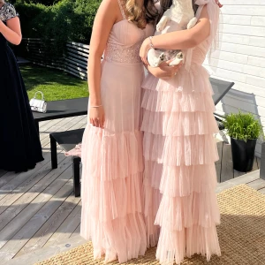 Ljusrosa balklänning med volanger - ⚠️RESERVERAD⚠️Elegant ljusrosa balklänning  med volanger och pärldetaljer på överdelen.  Klänningen är bra i längden på mig som är 165 och har klackar som är ca 5-7 cm höga. Såå vacker och får en verkligen att sticka ut på balen! Går ej att köpa längre så du kan vara säker på att ingen kommer ha en likadan😉 Köptes för 1500 men säljer för 950, endast använd en gång!❤️