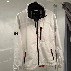 Vit vindjacka från Helly Hansen - Säljer en stilren vit vindjacka från Helly Hansen, perfekt nu när våren närmar sig! Nästintill nyskick  | Nypris: ca 2000kr - Mitt pris: 699kr 