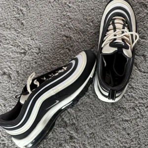 Nike Air Max 97 modell ”black sail” - Hej, säljer Snygga Nike Air Max 97 sneakers i svart och vit. Som är i mycket bra skick. Skorna kostar runt 2600-3000kr och är en ovanlig modell. Skriv vid minsta lilla fråga? 