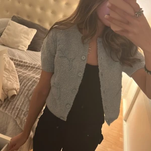 Ljusblå kofta från Zara - Säljer en söt ljusblå kofta från Zara med korta ärmar och knappar framtill. Koftan har ett diskret blommönster och är tillverkad i ett mjukt material som ger en mysig känsla. Perfekt för lager-på-lager-stil.