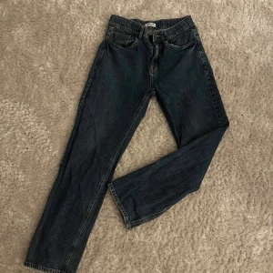 Blå jeans från Lindex - Säljer ett par klassiska blå jeans från Lindex. De har en rak passform med fem fickor och knappgylf. Perfekta för en avslappnad stil. Storlek 170.