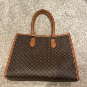 Brun mönstrad axelväska - Säljer en stilren brun handväska med ett elegant mönster. Väskan har bruna handtag och detaljer, samt en praktisk dragkedja inuti. Perfekt för att bära dina dagliga nödvändigheter med stil. Pris kan alltid diskuteras såklart!💞(väskan städas noga innan frakten som också köparen står för)