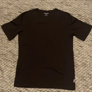 Mörkgrå J&J T-Shirt - Tja, säljer denna snygga mörkgrå T shirten från Jack & Jones. Funkar Man som Kvinna alltså Unisex. Tröjan har legat i garderoben ett tag därefter rynkorna men går lätt att stryka till
