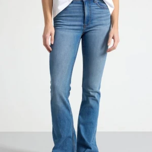 Blå bootcut jeans från Lindex - Säljer ett par snygga blå bootcut jeans från Lindex i storlek 38. De är högmidjade och har en klassisk femficksdesign med knapp och dragkedja. Perfekta för både vardag och fest! 💙